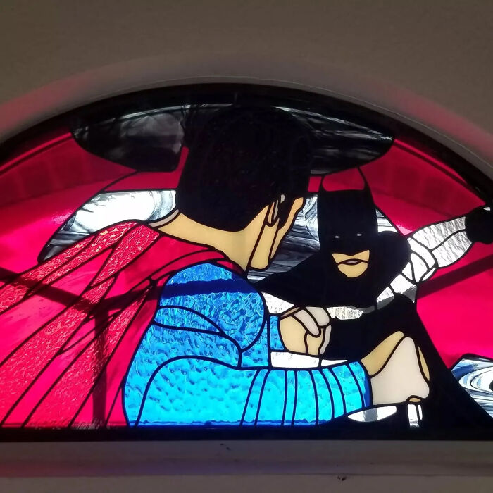 Stained glass sign depicting pop culture icons Batman and Superman in a vivid and colorful design.