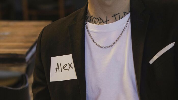 Person wearing a black blazer and white shirt with a name tag, representing ambiguous situations for fault and right voting.