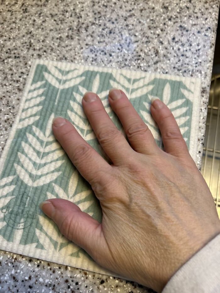 Hand pressing on a patterned cleaning cloth, one of 19 host gifts that say thank you for feeding me in style