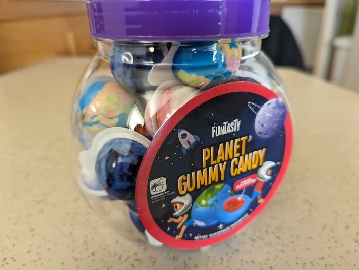 Container of planet-shaped gummy candy with colorful designs, a unique gift idea for never-before-seen gifts collection.