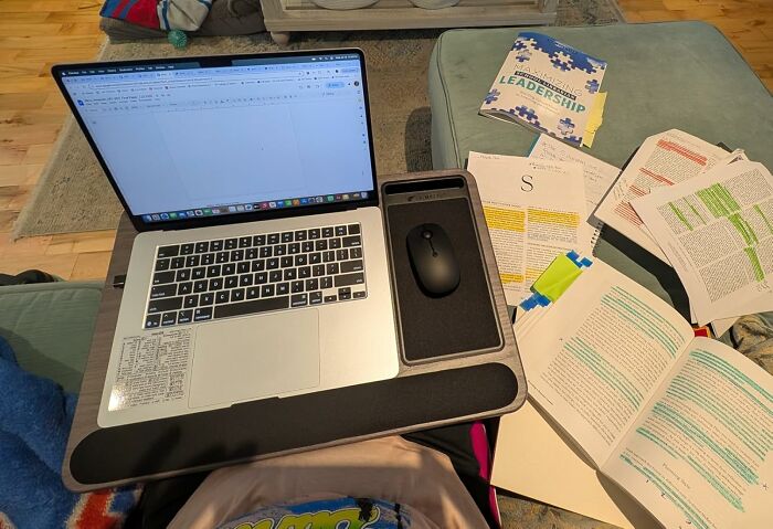 Laptop with mouse tray on lap surrounded by highlighted study notes and a book, featuring popular Amazon products for productivity.