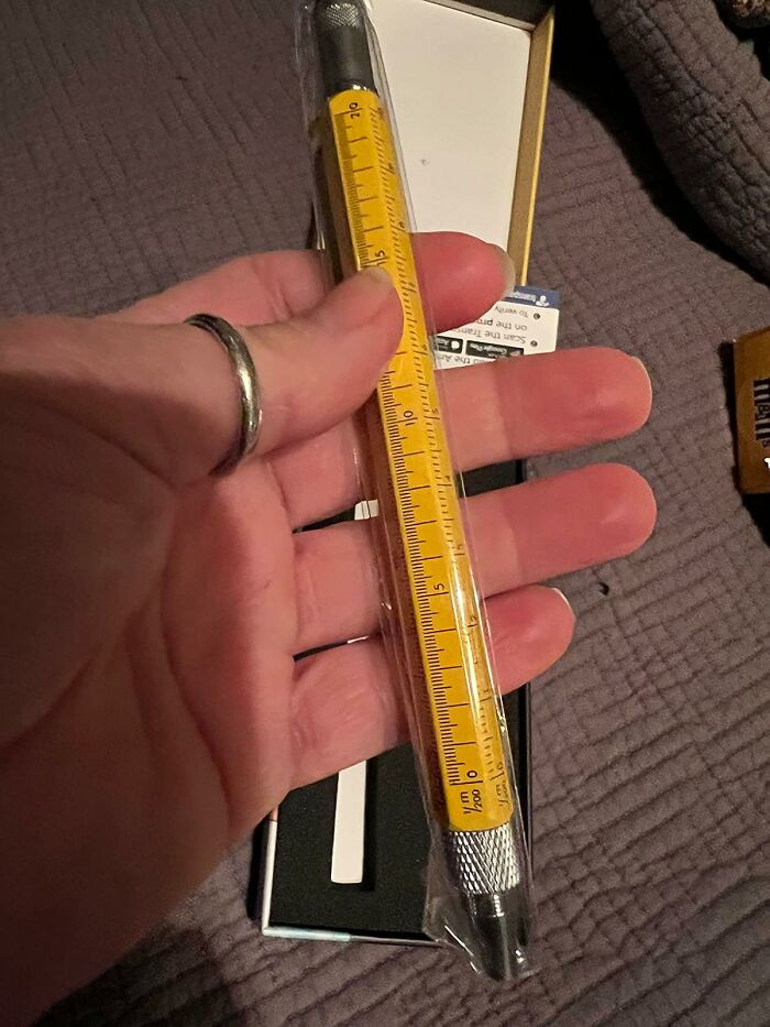 Hand holding a yellow multitool pen with ruler, a practical gift idea for last-minute guests not on Santa’s original list.