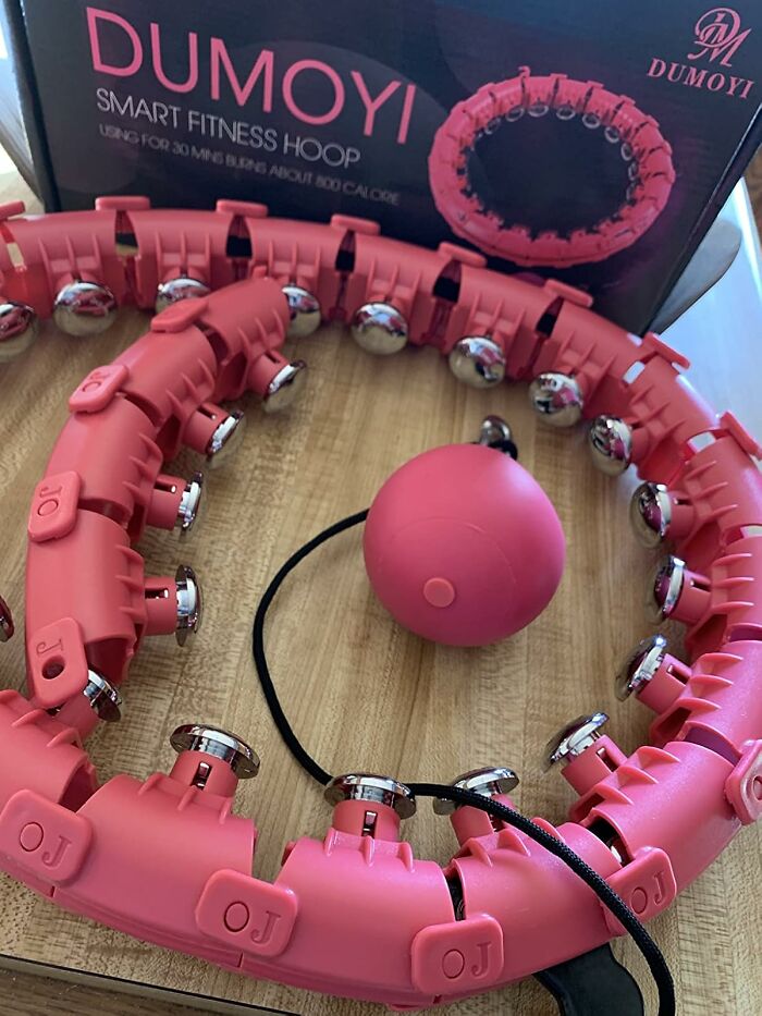 Red smart fitness hoop with weights on wooden surface for apartment friendly fitness goals.