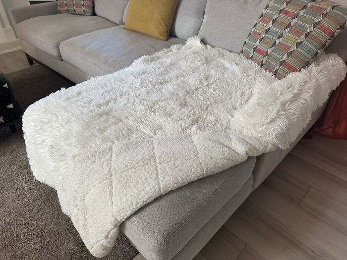 Cozy white faux fur throw blanket on a modern gray couch, perfect gift idea to impress your mother-in-law.
