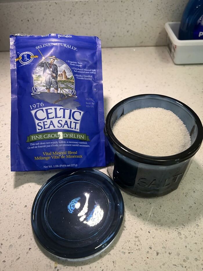 Celtic sea salt package and a blue salt cellar filled with fine ground salt on a kitchen counter.