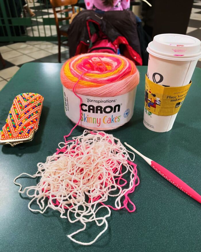 Colorful yarn cake, crochet hook, and coffee cup on a table, representing gifts in a Hobby Lobby craft isle.