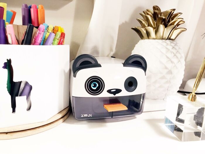 Desk setup with panda-shaped pencil sharpener, colorful markers, and decorative pineapple for teacher gifts and caffeine lovers.