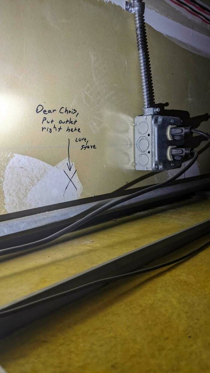 Handwritten note on wall directing where to put outlet with a metal outlet box already installed nearby in a random funny pic.
