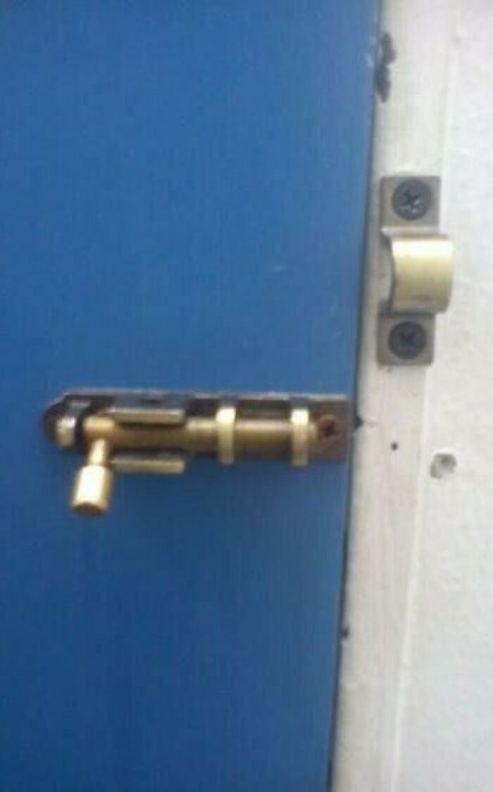 Door slide bolt installed incorrectly on a blue door, an example of pointless things that serve no purpose except being funny.