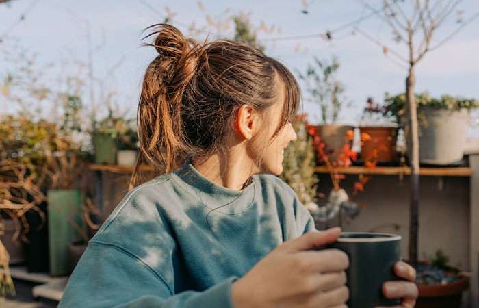 Young woman with hair in a ponytail holding a cup outdoors, illustrating what men find attractive in women traits.