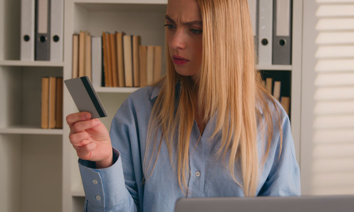 Woman looking worried holding credit card at home, representing SAHM at a loss after unexpected divorce news. Woman looking worried holding credit card at home, representing SAHM at a loss after unexpected divorce news.