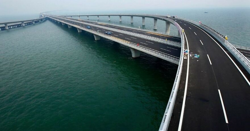 Aerial view of a long curved bridge over the sea, showcasing remarkable engineering of the longest bridges in the world. Weinan Weihe Grand Bridge, China