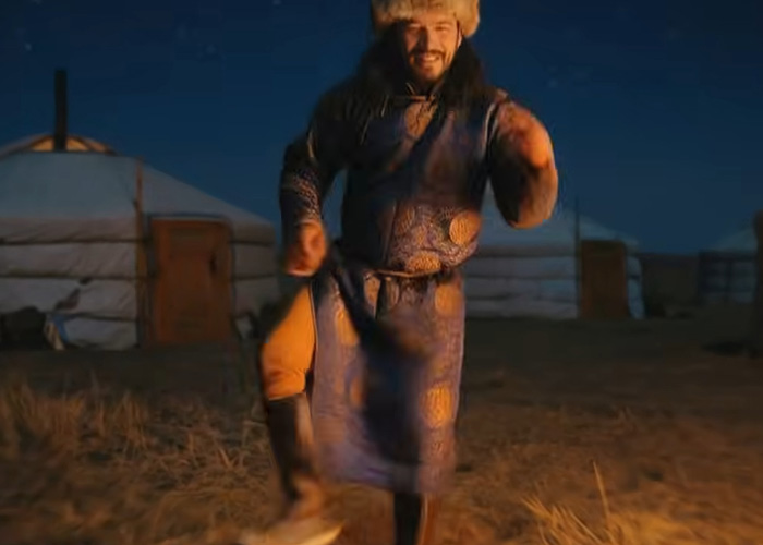 Mongolian man in traditional clothing performing throat singing outdoors at night near yurts for viral Christmas anthem. Mongolian man in traditional clothing performing throat singing outdoors at night near yurts for viral Christmas anthem.