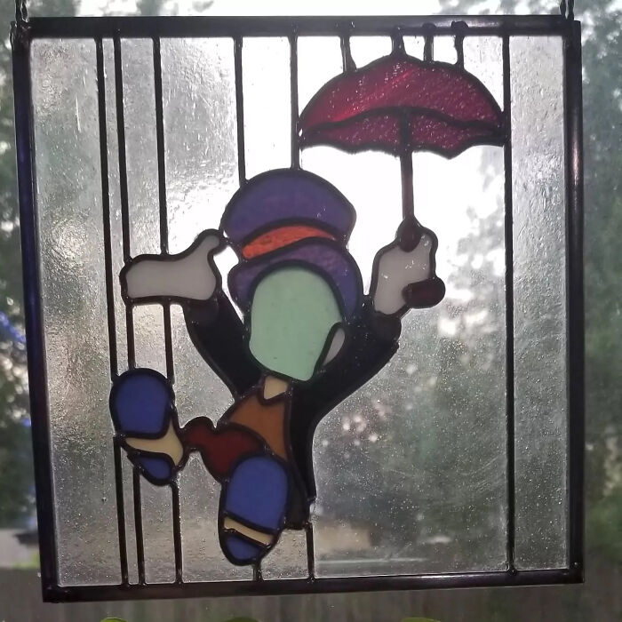 Stained glass art of a pop culture icon holding an umbrella, showcasing vivid colors and intricate design details.