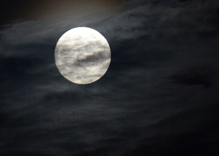 Full moon partially covered by dark clouds at night, illustrating eerie atmosphere for 911 operators and non-emergency calls.