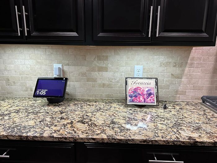Granite kitchen countertop with dark cabinets, smart display, and decorative focaccia sign, featuring popular Amazon wish list products.
