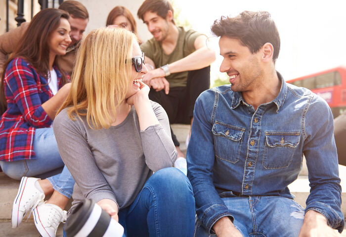 Group of friends socializing outdoors, showing signs someone is still stuck in their high school era years later.