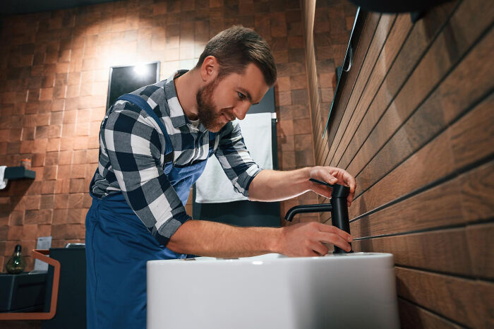 Man fixing bathroom faucet, an embarrassing moment people were blessed to see when others thought no one was looking