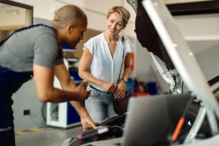 Mechanic explaining car issues to a woman, representing one of the most bizarre things people ever seen just taking a glance through a neighbor’s window.