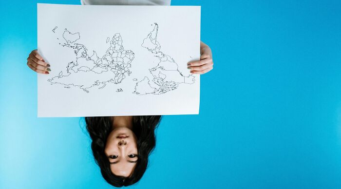 Person holding a rotated map featuring outlines of 28 countries, challenging geography nerds to guess each one.