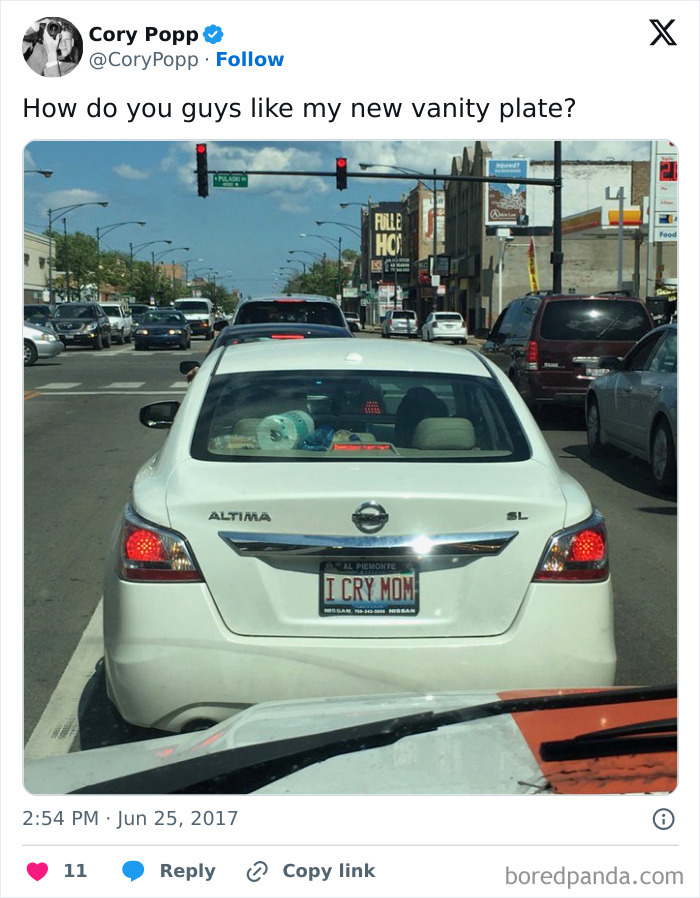 White Nissan Altima with a hilarious personalized license plate reading I CRY MOM stopped at a red light in traffic.