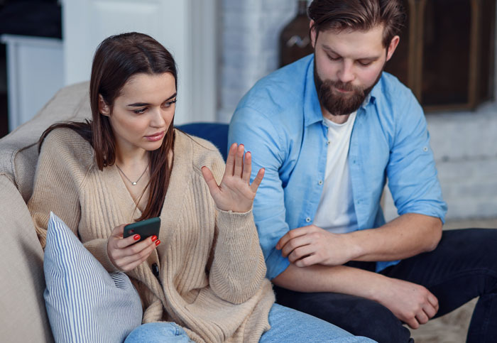 Couple having a serious conversation on a couch, illustrating forgiveness and challenges in relationships.
