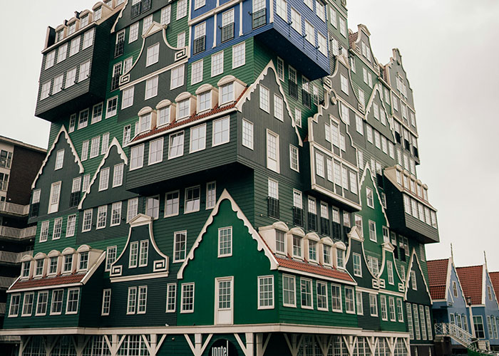 Stacked green and blue houses with white trim in a unique architectural style, a place that looks AI generated but is real.