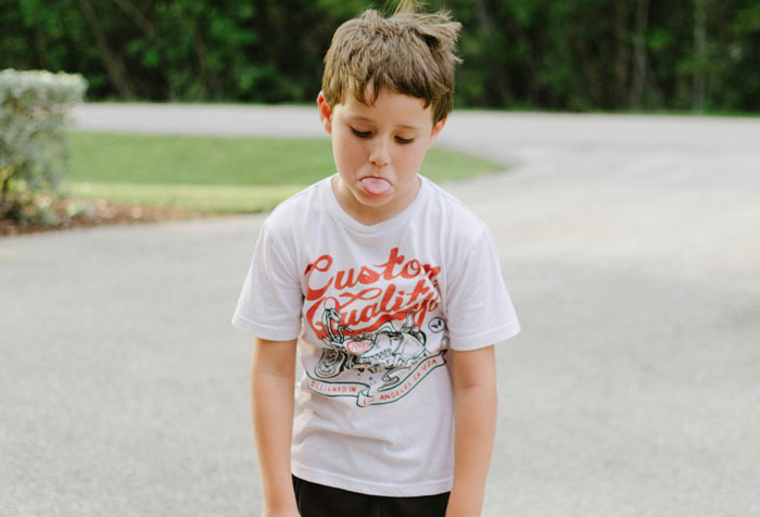 Young boy making a silly face outdoors, illustrating the concept of kids who are next-level evil in a playful way.