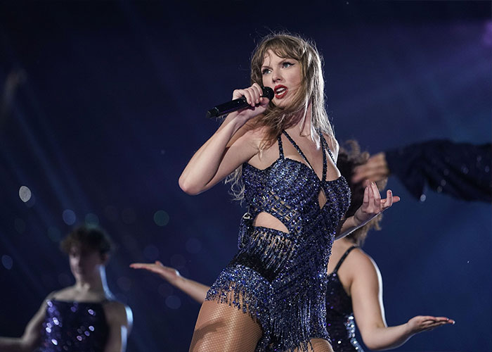 Taylor Swift performing on stage in a sparkling outfit amid fake conspiracy claims of coded white-nationalist messages.