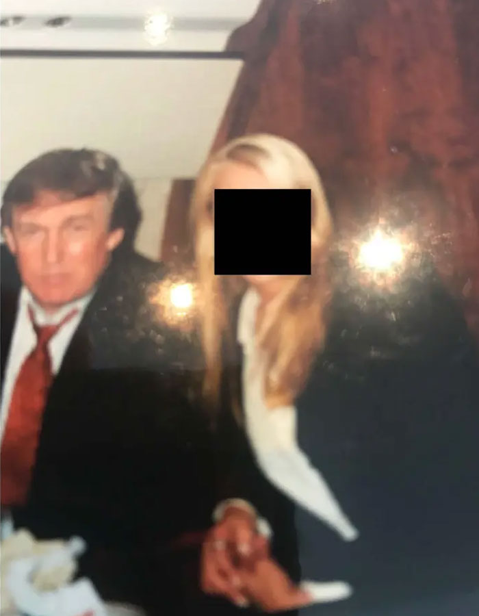 Blurry photo of a man and woman seated indoors, triggering backlash after disturbing Epstein desk photo release.
