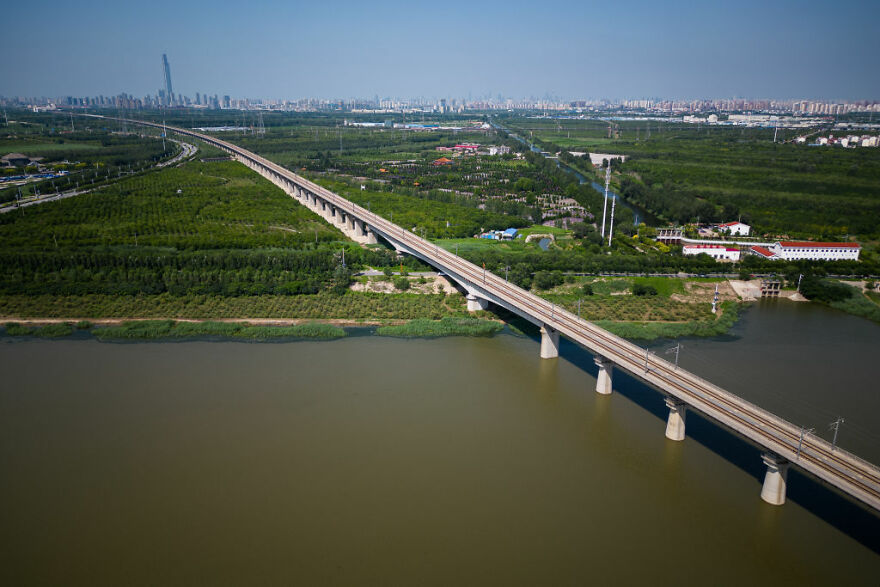 Aerial view of remarkable engineering in one of the 12 longest bridges in the world spanning across a river and green landscape.