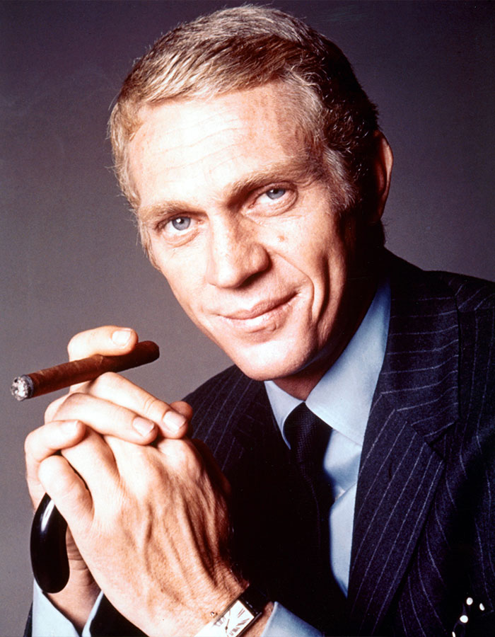 Actor in a pinstripe suit holding a cigar, representing outrageous demands actors have put in their contracts.