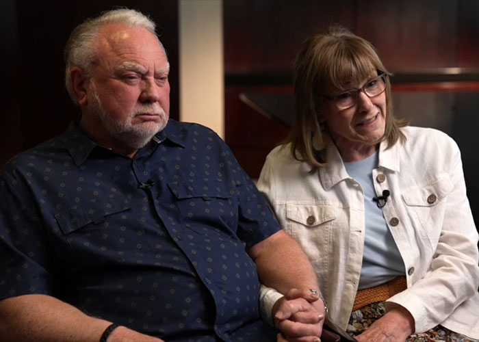 Older couple holding hands in an interview setting, reflecting on a patient’s haunting final post from dentist chair before fatal procedure. Older couple holding hands in an interview setting, reflecting on a patient’s haunting final post from dentist chair before fatal procedure.