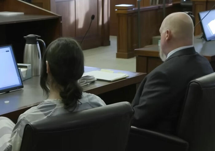 Trans Muslim woman sitting in courtroom next to lawyer during sentencing hearing after parents' passing case. Trans Muslim woman sitting in courtroom next to lawyer during sentencing hearing after parents' passing case.