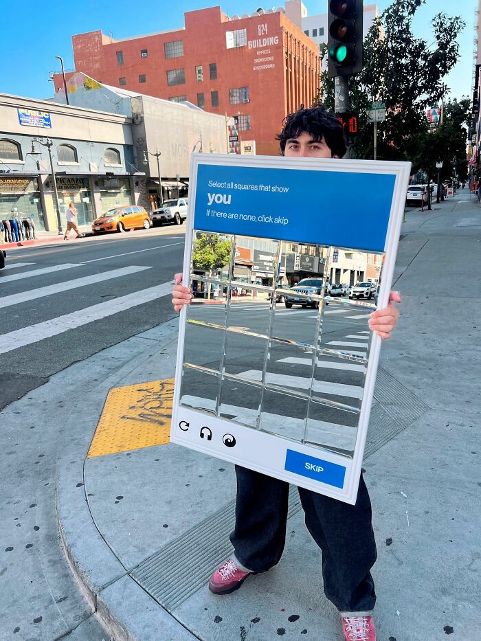 Person holding a reflective puzzle frame on a city street, creating a trippy picture that distorts reality.