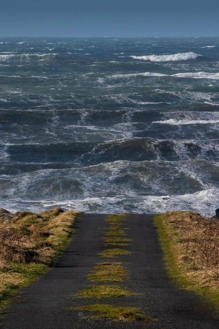 A coastal road abruptly ending at the ocean with rough waves, a place that looks AI generated but is actually real.