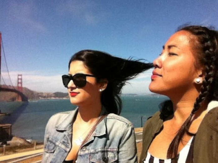 Two women captured in a funny, interesting, and weird pic with hair perfectly stretched by the wind near Golden Gate Bridge.
