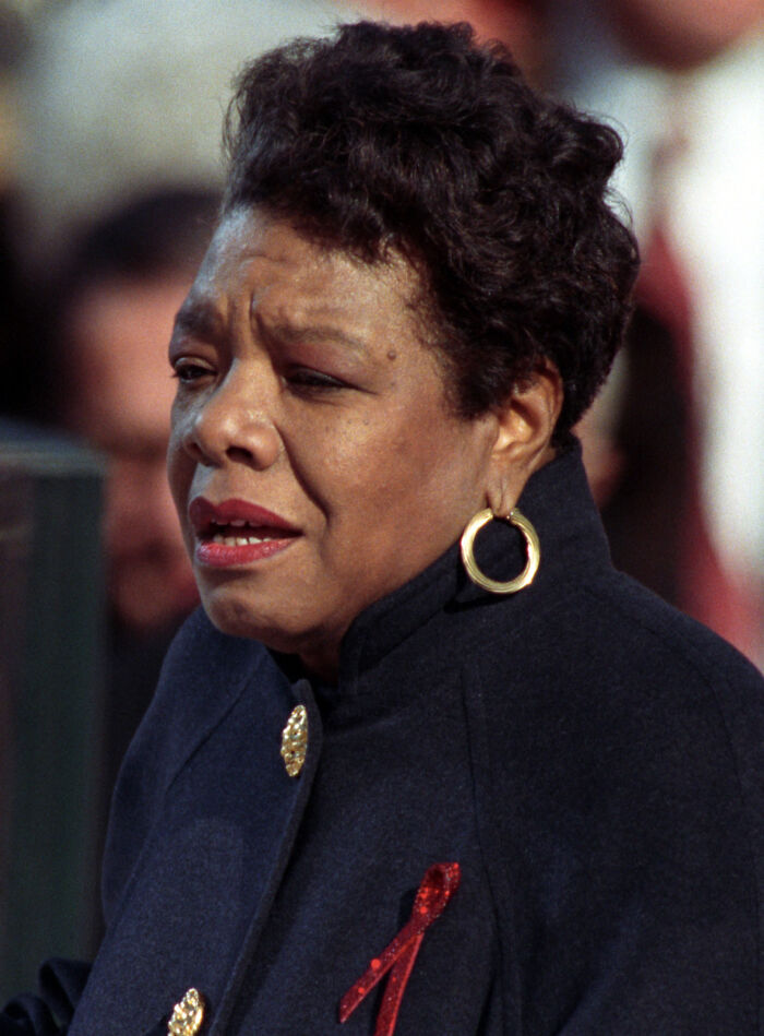Woman wearing gold hoop earrings and a dark coat with a red ribbon, expressing emotion in an outdoor setting, true stories theme.