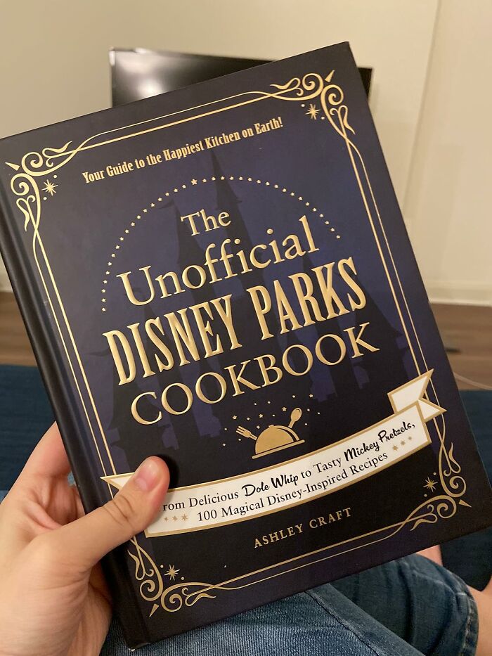 Hand holding The Unofficial Disney Parks Cookbook, a gift idea for last-minute guests not on Santa’s original list.
