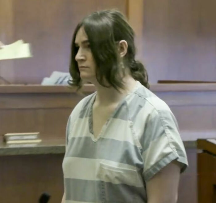 Trans Muslim woman in striped prison uniform standing in courtroom during sentencing hearing. Trans Muslim woman in striped prison uniform standing in courtroom during sentencing hearing.