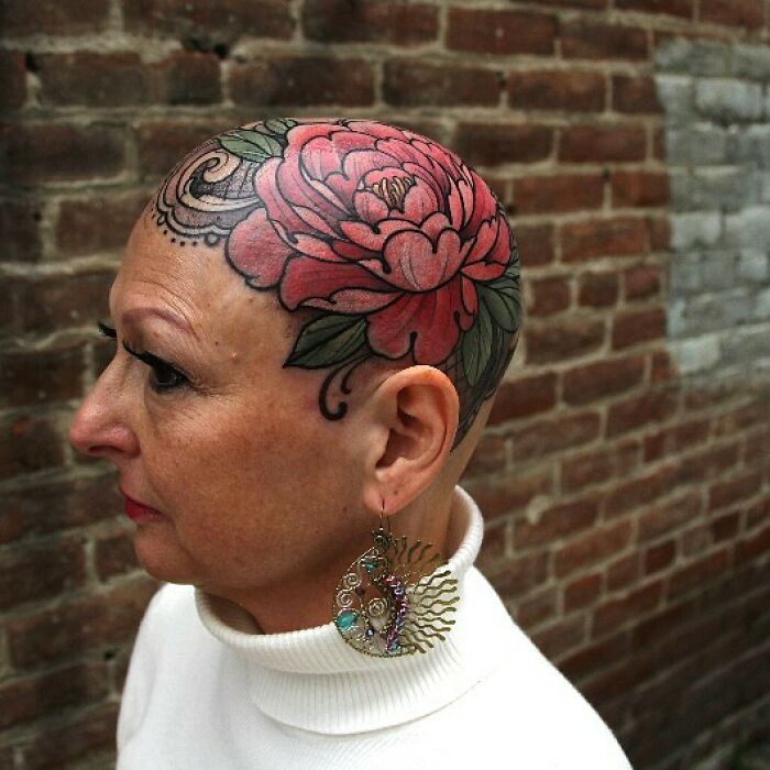 Woman with a large, colorful flower tattoo covering her shaved head, showcasing wholesome tattoos with deep meaning. Woman with a large, colorful flower tattoo covering her shaved head, showcasing wholesome tattoos with deep meaning.