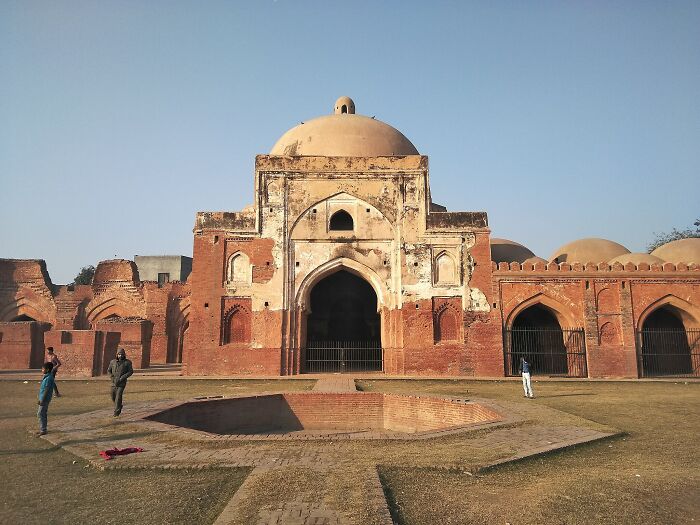 Ancient red brick structure with dome and arches, visitors walking around, illustrating horrifying wedding tragedy and missing child case.