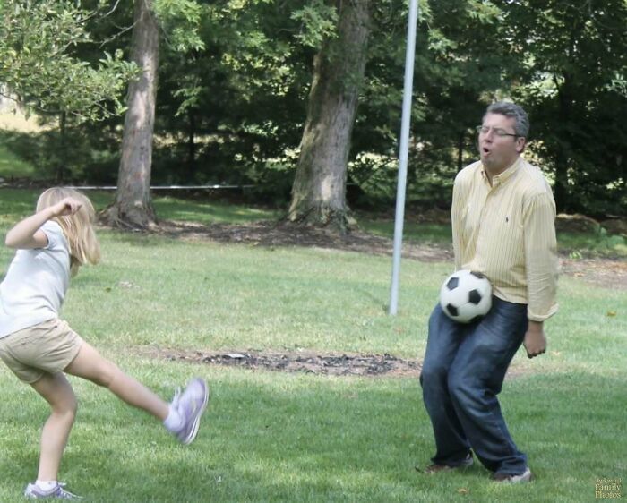 Man reacting with a funny expression as a soccer ball hits him while playing outdoors at the perfect moment.