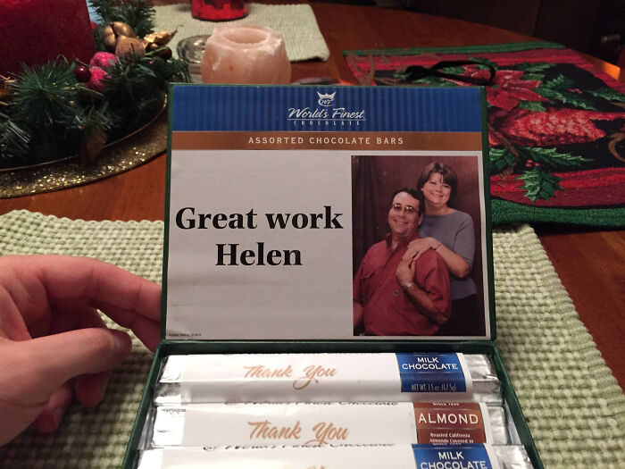 Box of assorted chocolate bars as bizarre Christmas gifts with personalized label reading Great work Helen and photo inside.