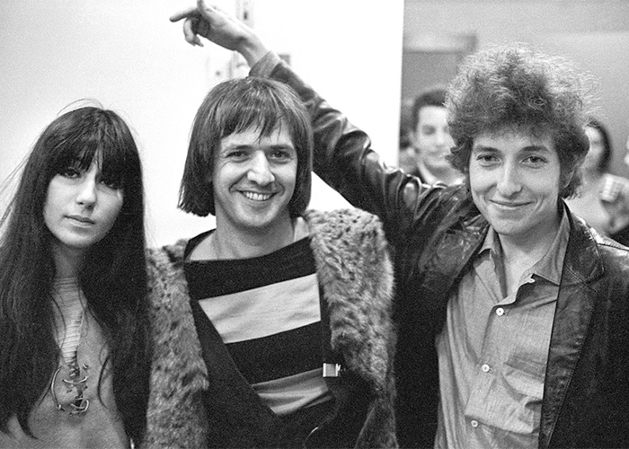 Rarely-seen pop culture shot of three iconic musicians smiling and posing together in a casual backstage setting.
