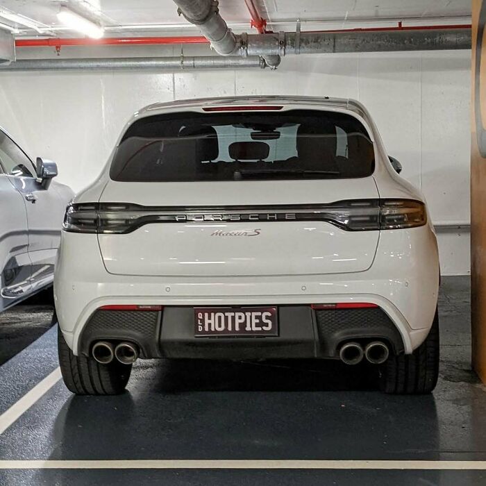 White Porsche Macan S with personalized license plate HOTPIES parked in an indoor garage, showcasing hilarious license plates.
