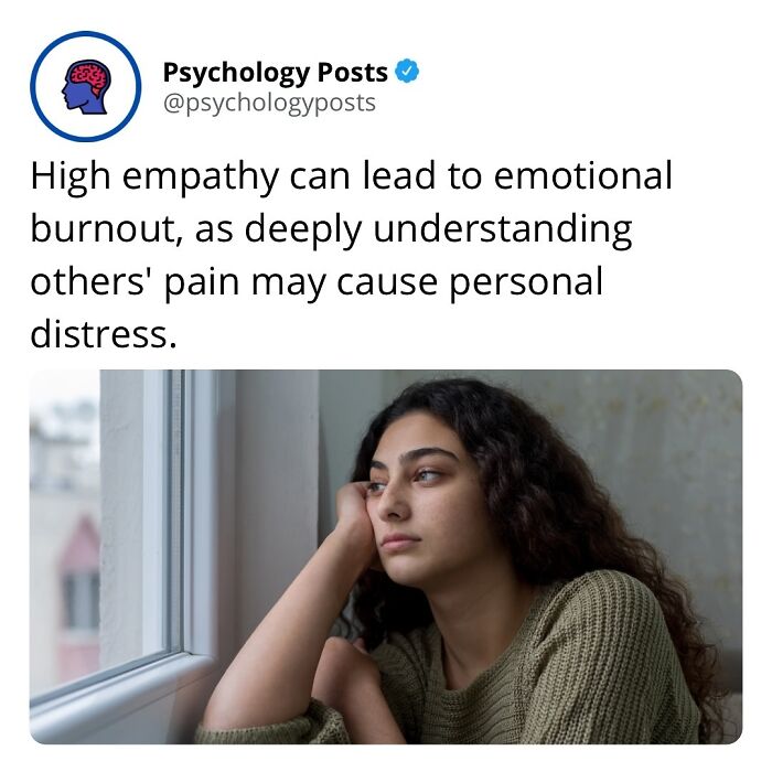 Young woman with curly hair wearing a green sweater looking pensive by a window, illustrating psychology facts on empathy.