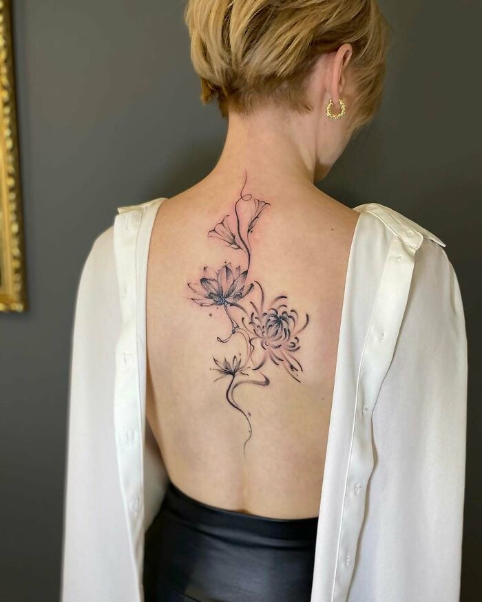 Delicate floral tattoo on woman’s back showcasing wholesome tattoos with meaningful and elegant ink design.