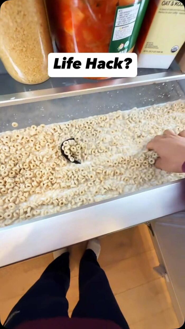 Person using a cereal drawer filled with Cheerios inside a dude fridge kitchen setup with containers above.
