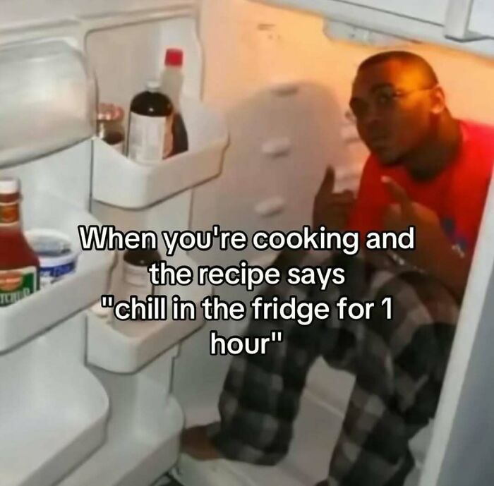 Man sitting inside an open fridge illustrating a funny dude fridge moment with kitchen condiments visible inside.